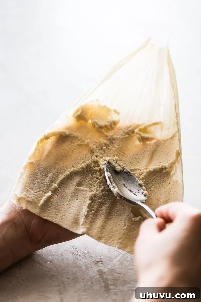 Unwrap the Flavor: Authentic Mexican Tamales 11 Fresh masa dough being expertly spread onto a corn husk for tamales.