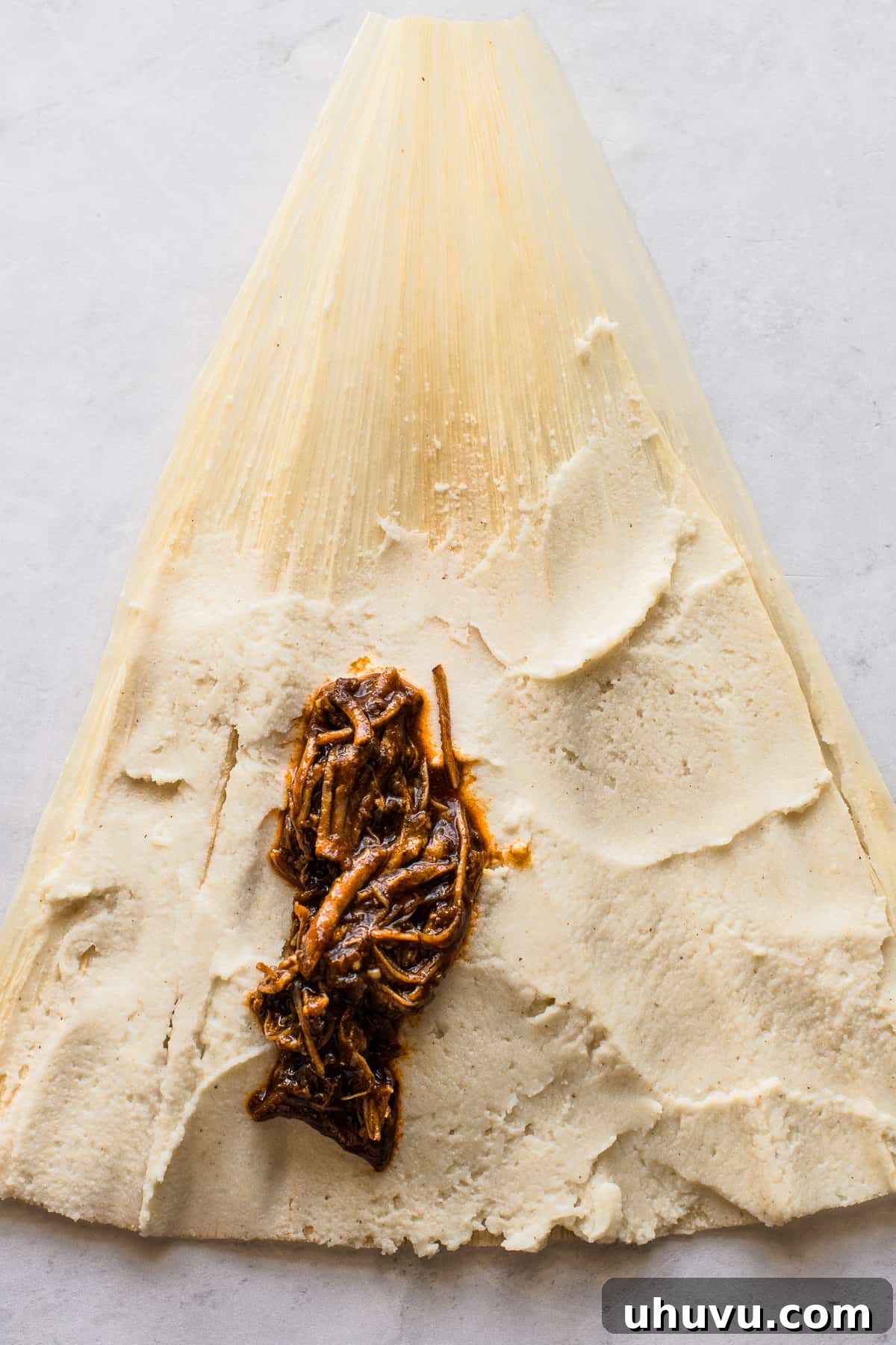 Unwrap the Flavor: Authentic Mexican Tamales 12 Shredded red chile pork filling carefully placed on fresh masa dough on a corn husk.