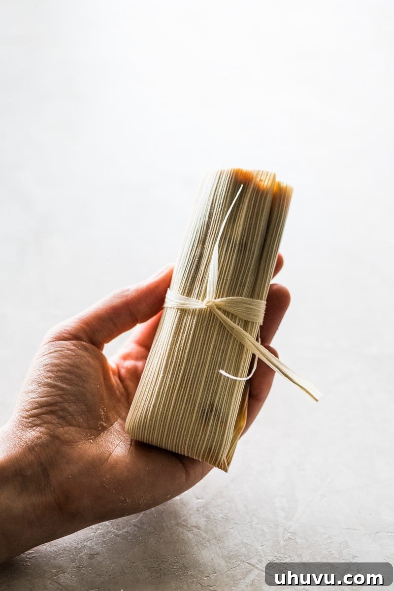 Unwrap the Flavor: Authentic Mexican Tamales 4 A perfectly cooked tamal being held in someone's hand, showing its tender masa and rich filling.