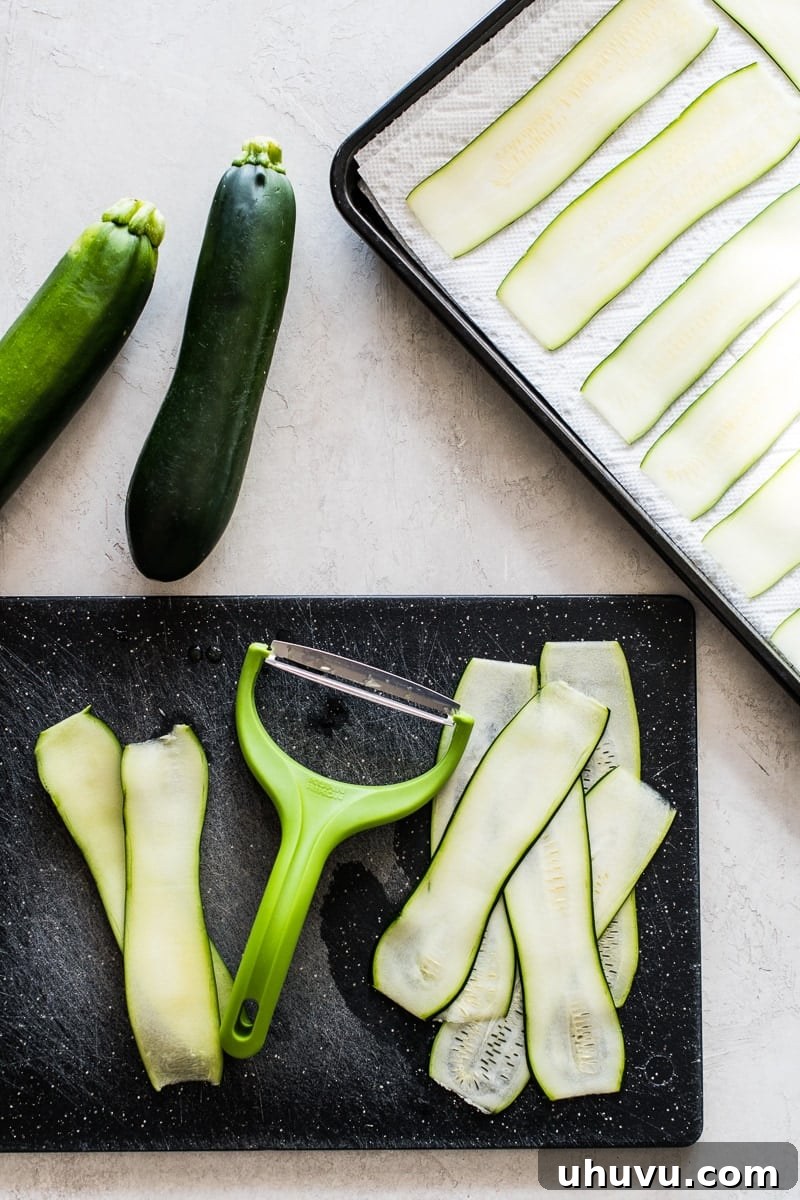 Southwestern Zucchini Roll-Ups 4 Thinly sliced zucchini ribbons neatly arranged on a cutting board, ready for use.
