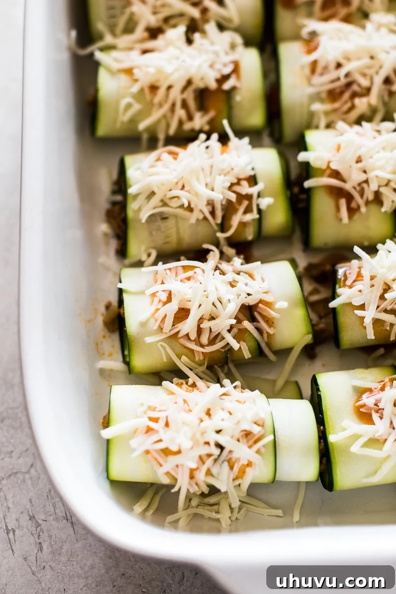 Southwestern Zucchini Roll-Ups 6 Rolled zucchini enchiladas, beautifully topped with rich sauce and shredded cheese, ready for the oven.