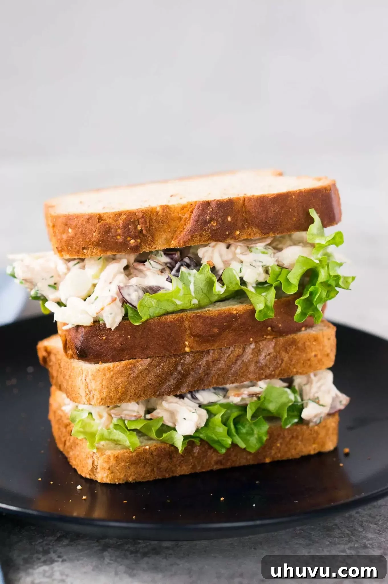 Stacked chicken salad sandwiches on a plate, ready to be served, emphasizing the generous filling and appealing presentation.