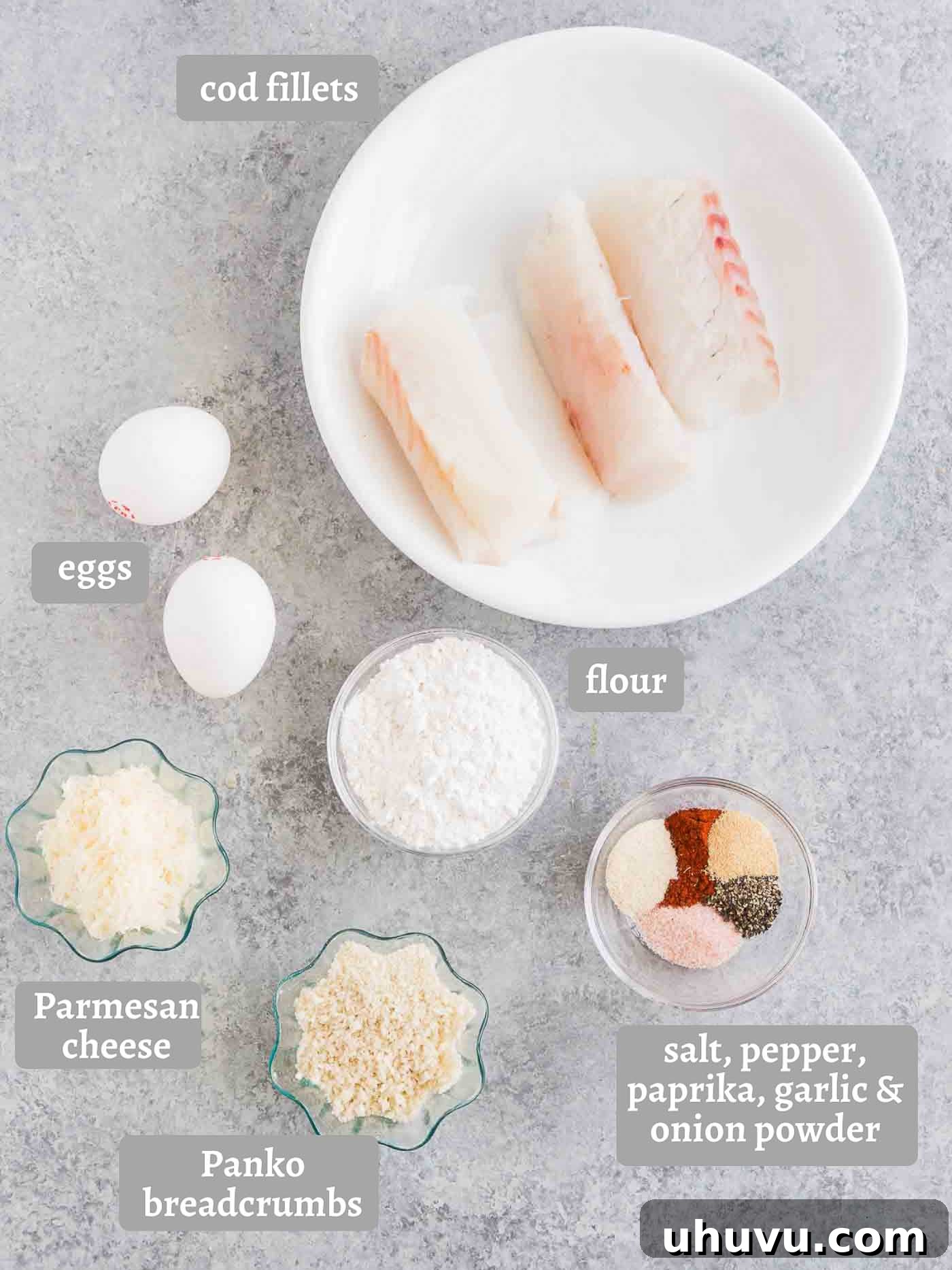 A flat lay photograph showcasing all the fresh ingredients required to make delicious homemade fish sticks, including cod fillets, panko, eggs, flour, and spices.