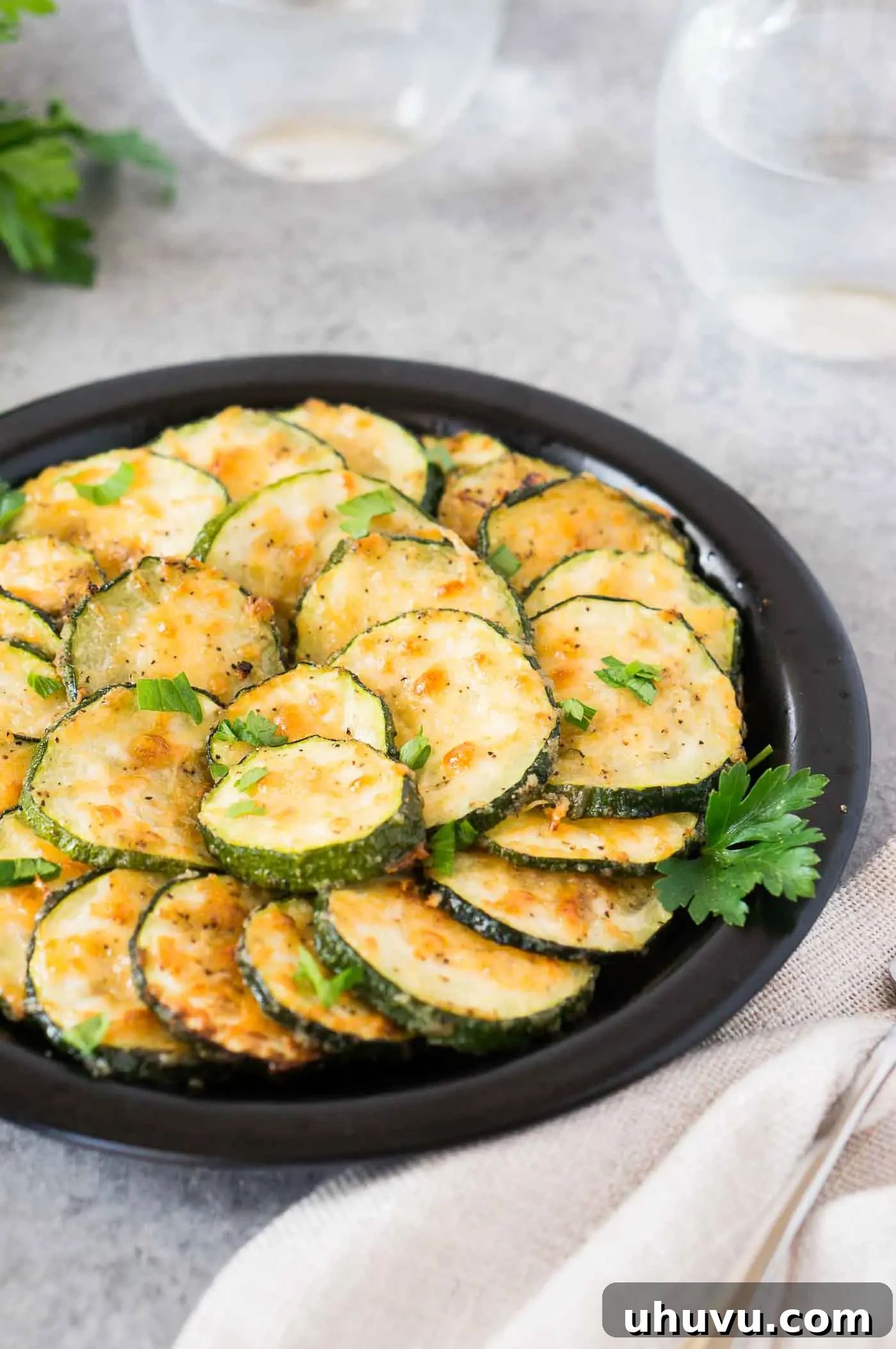 Golden Roasted Zucchini 7 A dish of garlic Parmesan zucchini rounds, expertly roasted to a golden-brown finish, presented on a white plate ready for serving.