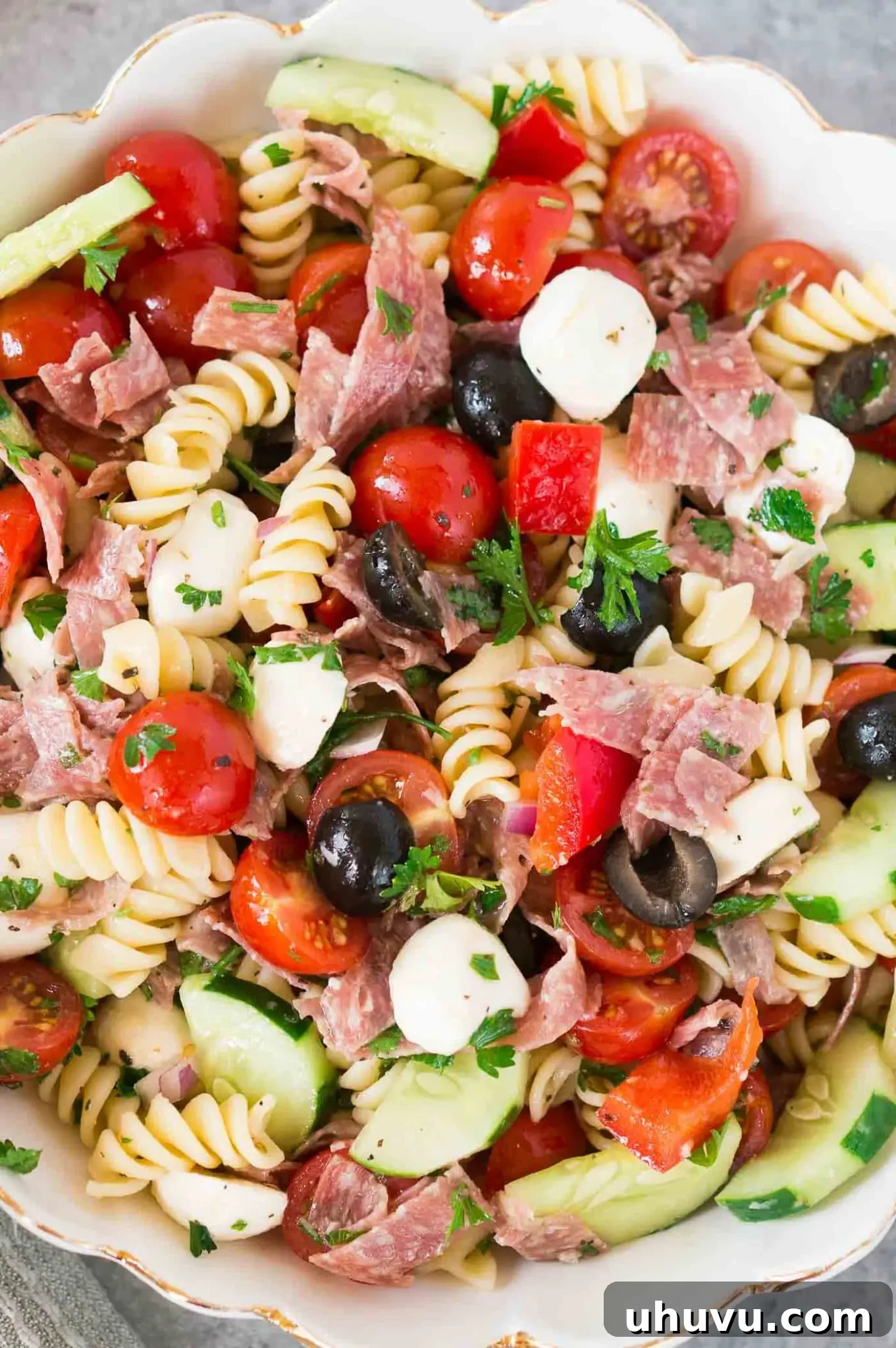 Close-up shot of the vibrant Italian pasta salad in a bowl, highlighting the texture of the pasta and fresh ingredients.