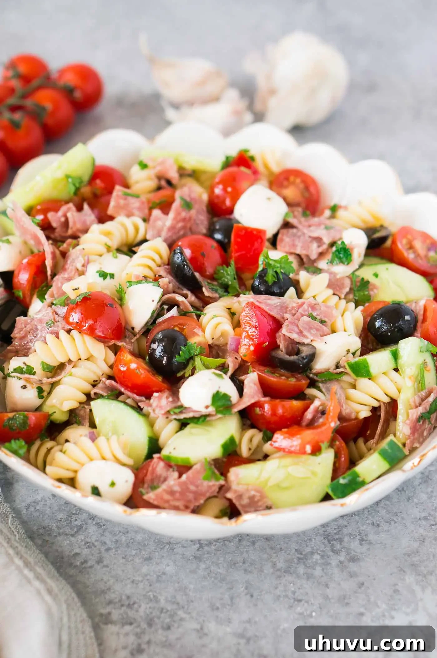 Vibrant Italian Pasta Salad 9 Large bowl of Italian pasta salad with mozzarella pearls, salami strips, cherry tomatoes, and cucumber, ready to be served.
