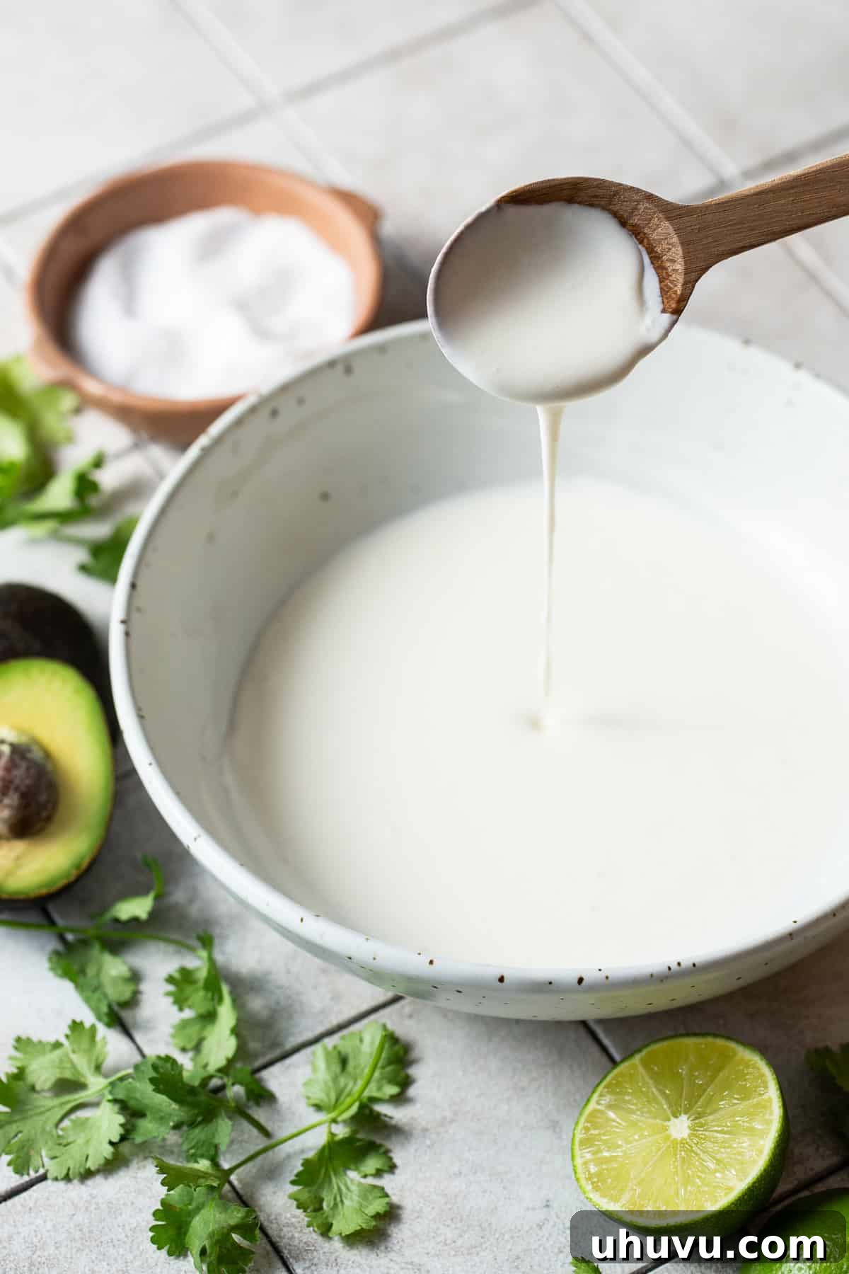 Mexico's Creamy Secret 5 A spoon stirring and pouring some finished Mexican crema into a bowl.