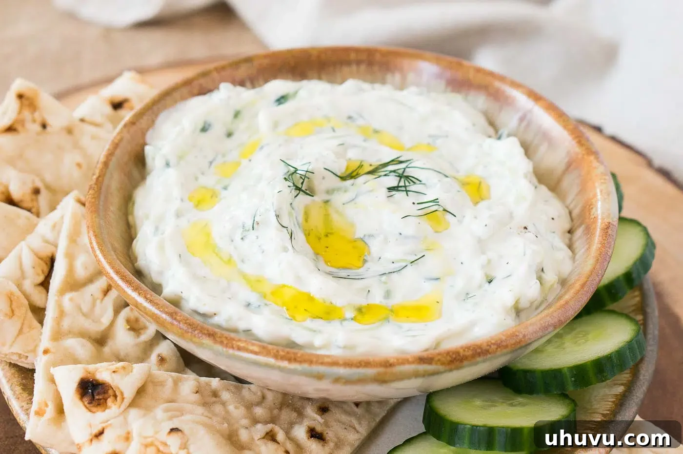 Freshly made Tzatziki dip in a white bowl, garnished with a sprig of fresh dill, ready to be served.