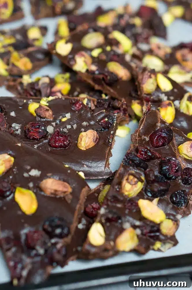 Close-up of cranberry pistachio chocolate bark pieces on a white background, highlighting the textures and colors.