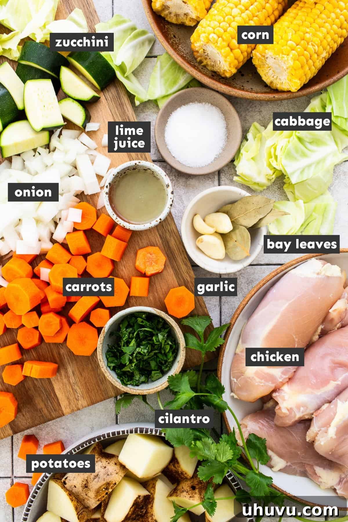 Wholesome Chicken Comfort 3 Fresh ingredients for Caldo de Pollo, Mexican chicken soup, neatly arranged on a wooden table, including bone-in chicken thighs, carrots, zucchini, corn, potatoes, cabbage, garlic, bay leaves, cilantro, and limes.