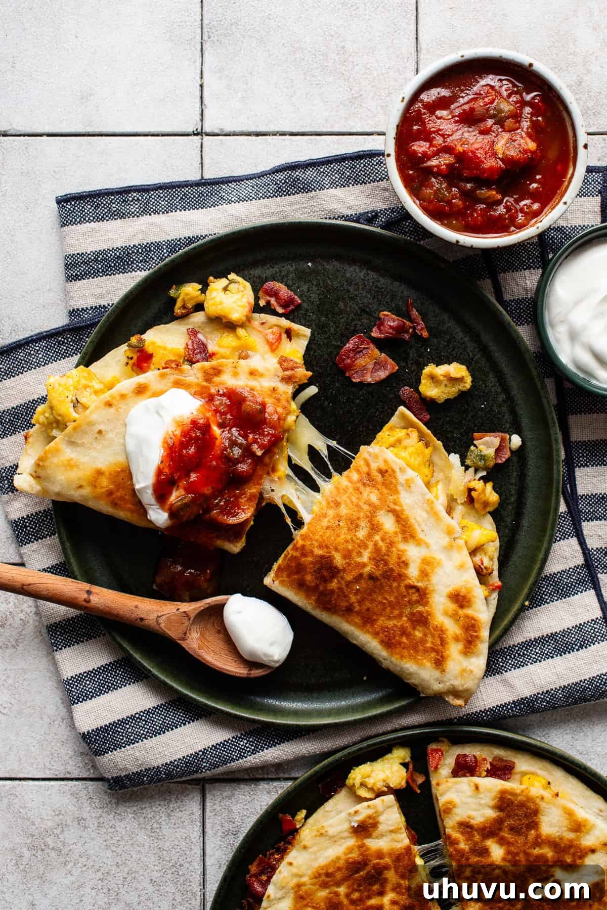 Savory Morning Quesadillas 2 A golden-brown breakfast quesadilla, sliced in half, revealing a mouth-watering cheese pull and a delicious filling of eggs, bacon, and vibrant vegetables.