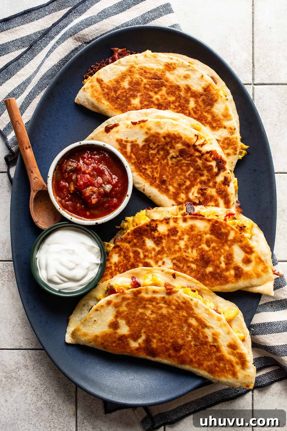 Savory Morning Quesadillas 6 Four golden-brown and crispy breakfast quesadillas arranged on a plate, garnished and served with fresh salsa and a dollop of sour cream.