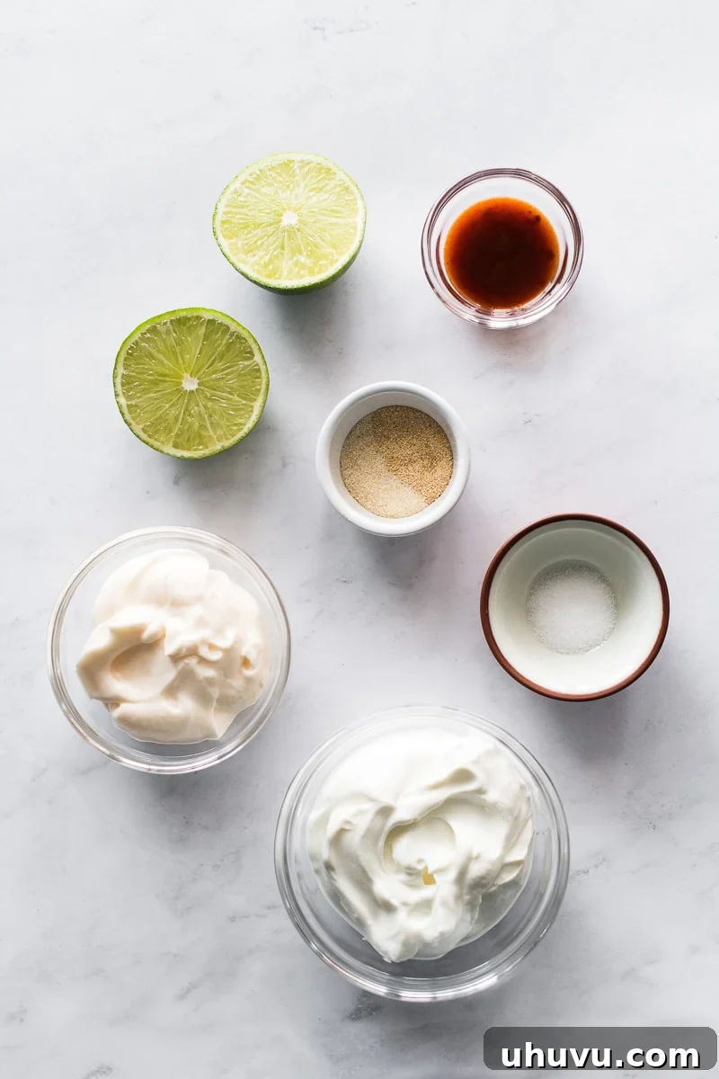 Baja Fish Taco Crema 3 All the essential ingredients for making fish taco sauce, including sour cream, mayonnaise, lime, garlic powder, onion powder, and adobo sauce, neatly arranged on a rustic wooden table.