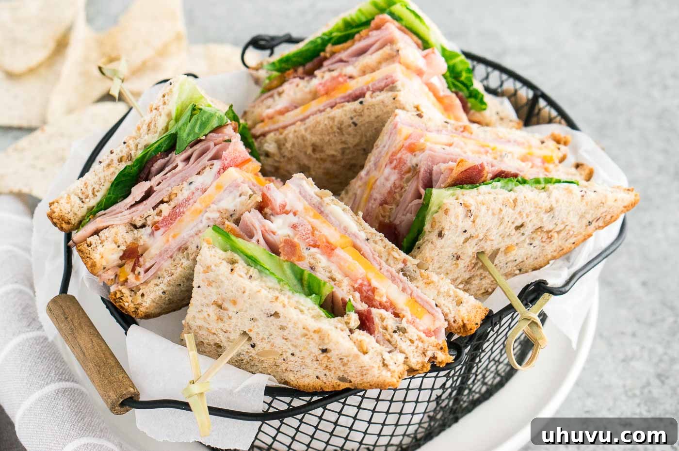 A close-up image of two perfectly cut club sandwiches, showcasing their delectable layers and crispy bacon, served in a rustic basket.