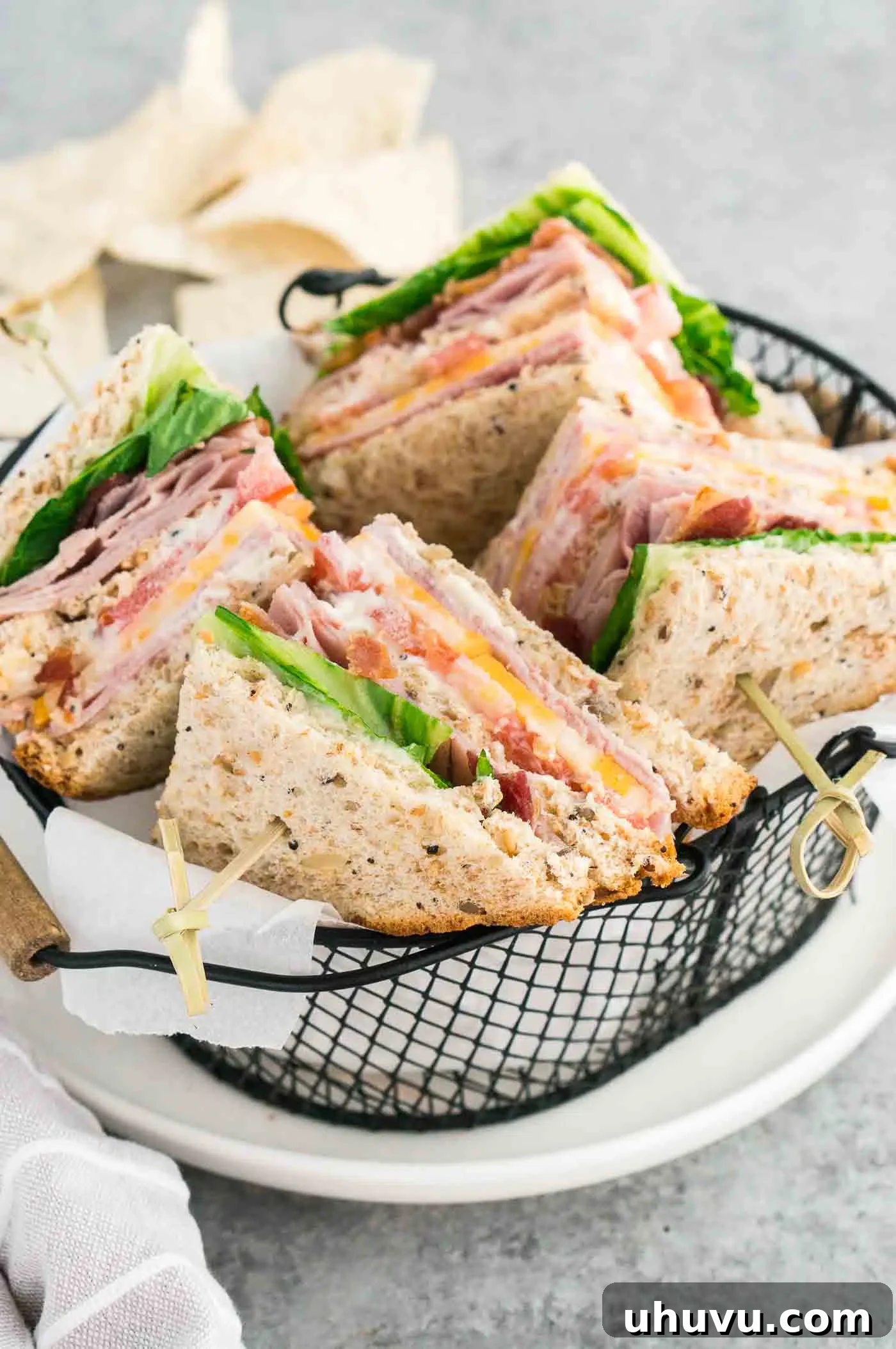 Two club sandwiches, artfully cut into triangles and secured with toothpicks, nestled in a small basket, ready to be enjoyed.