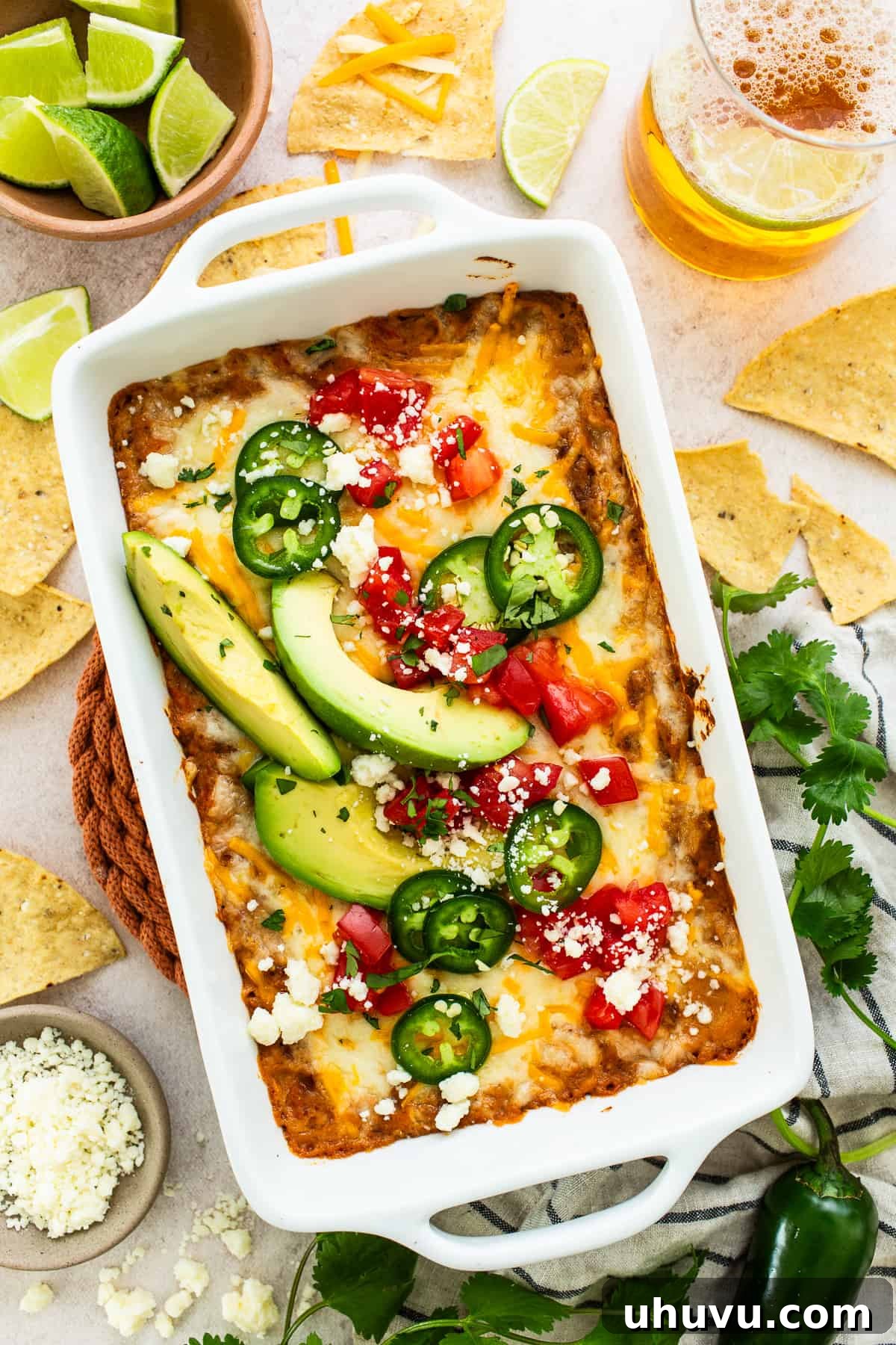 25 Quick Bean Dinners 6 Creamy Bean Dip, topped with irresistible melted cheese and garnished with fresh diced tomatoes, crumbly cotija cheese, vibrant sliced peppers, and creamy avocado.