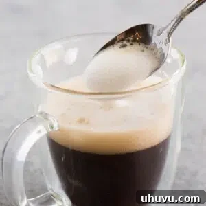 Spoon frothy milk over coffee