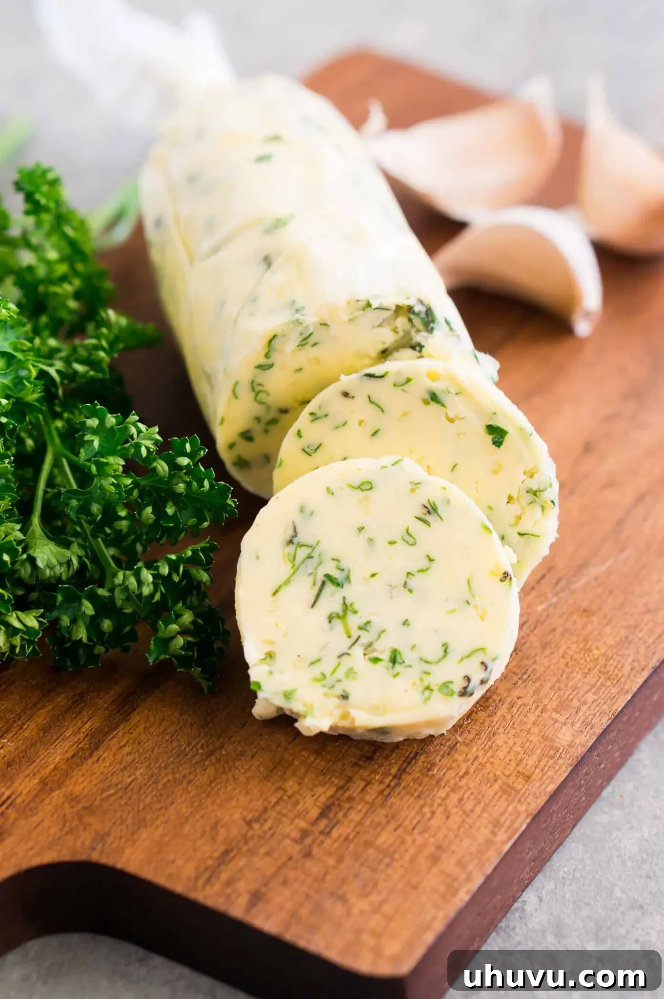 Sliced garlic and herb butter rounds on a wooden board, ready to serve