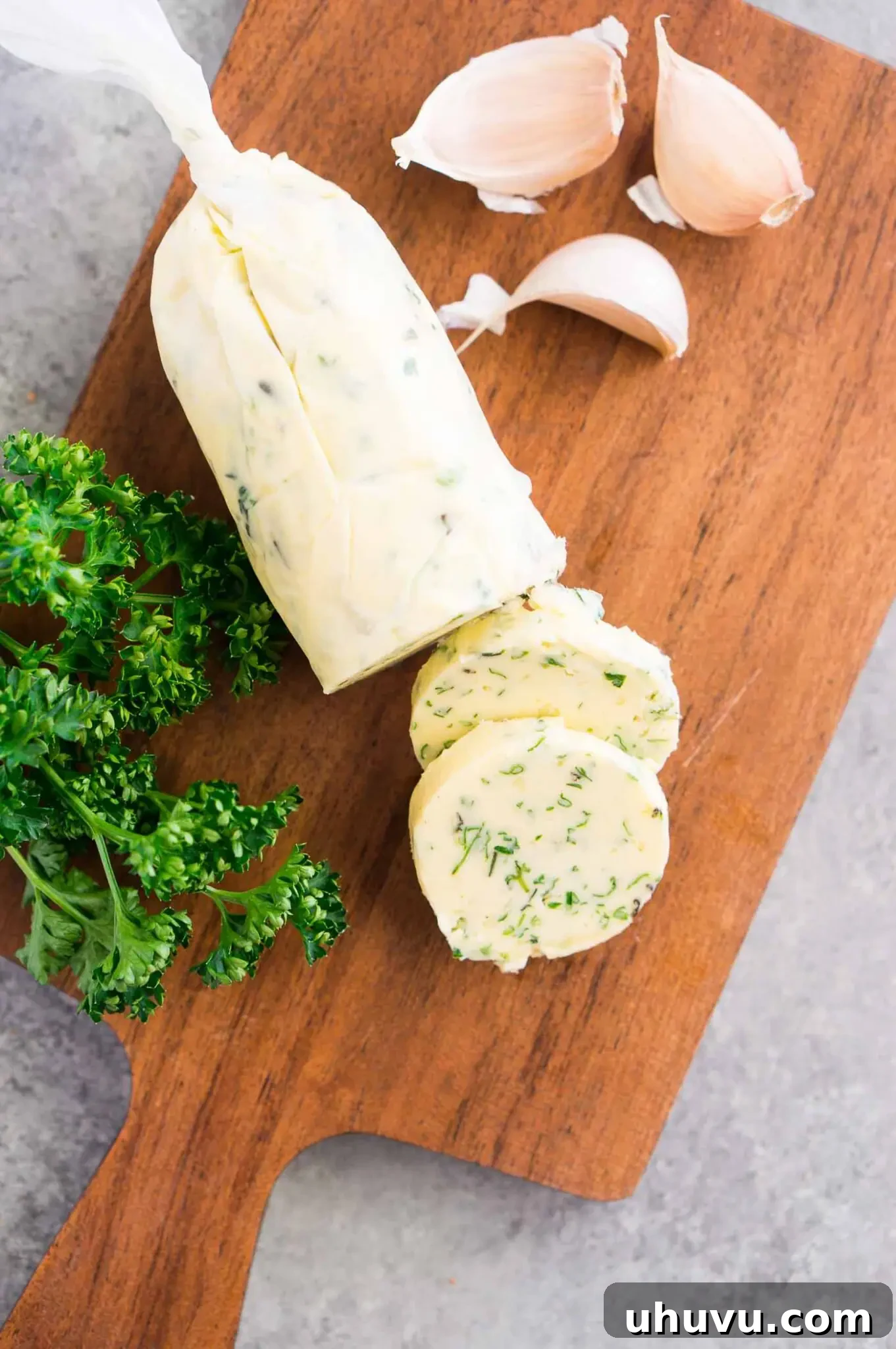 Wrapped compound butter log in parchment paper on a cutting board