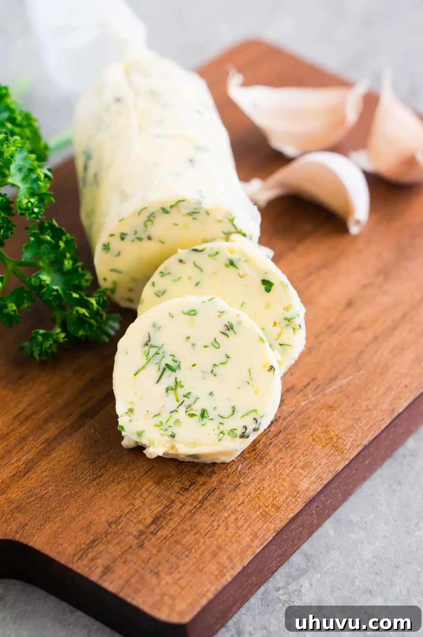 Compound butter wrapped in parchment paper and sliced on a wooden board