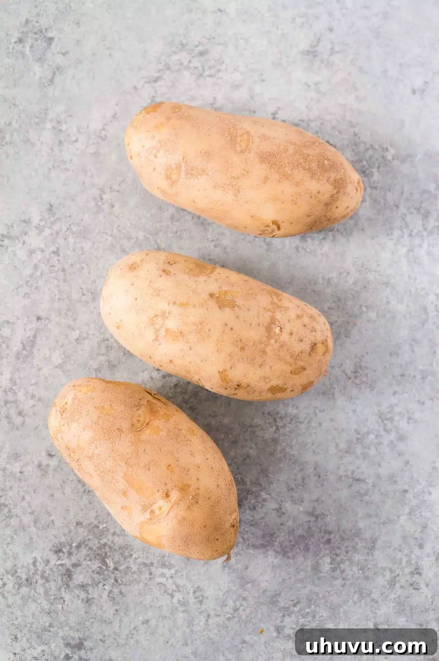 Fresh Russet potatoes on a wooden board, ready for cooking
