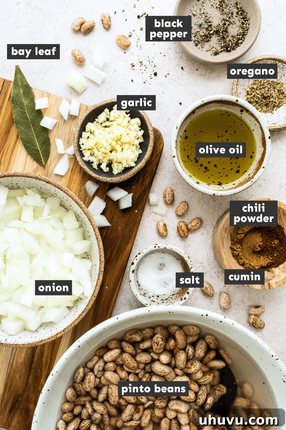 Ingredients for making pinto beans laid out in separate mixing bowls on a table.