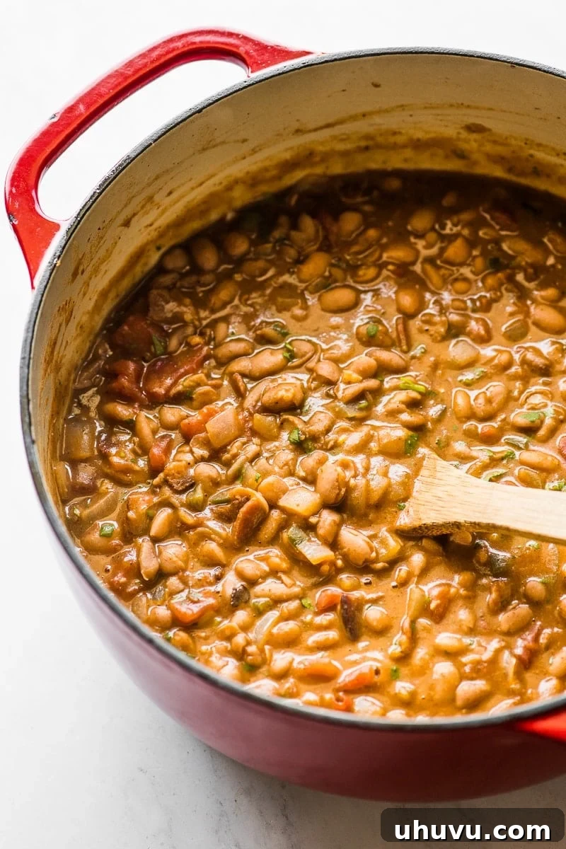 Beer-Braised Fiesta Beans 7 A vibrant pot of Borracho Beans, steaming hot and ready to be served, promising a rich and flavorful Tex-Mex experience.