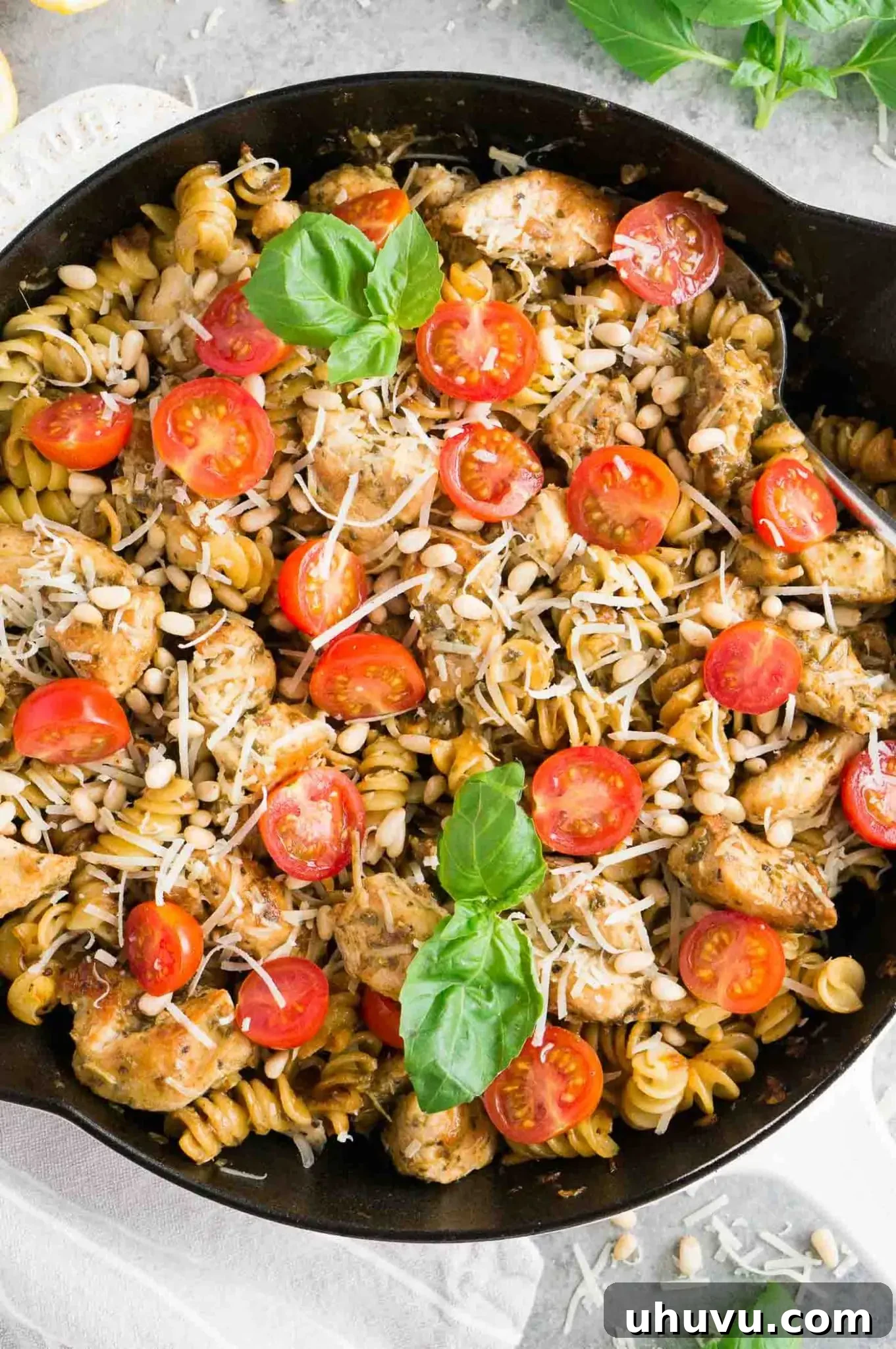 A large serving of pesto chicken pasta with cherry tomatoes