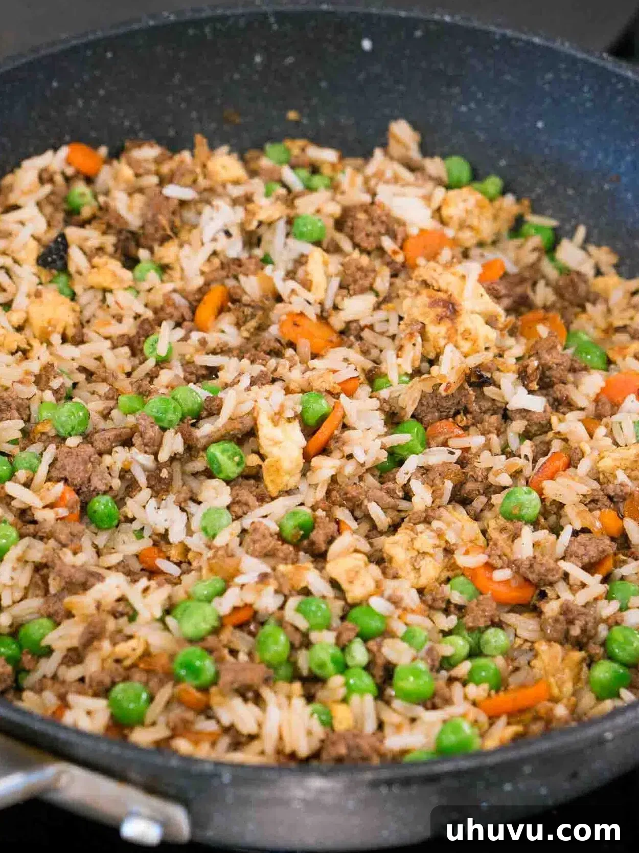 Wok-Fired Beef Rice 10 Finished ground beef fried rice with green peas and green onions, cooking on the stove