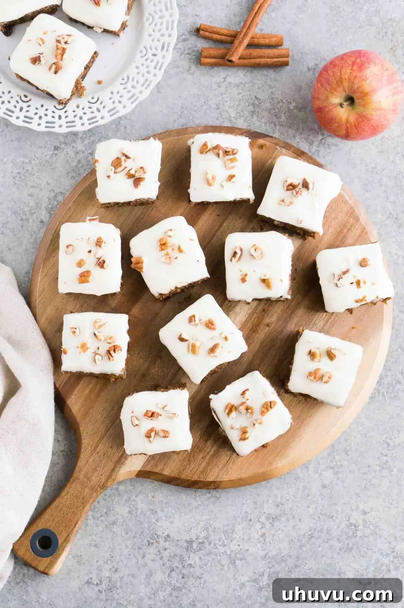 Applesauce cake bars arranged on a rustic wooden board, garnished with nuts.