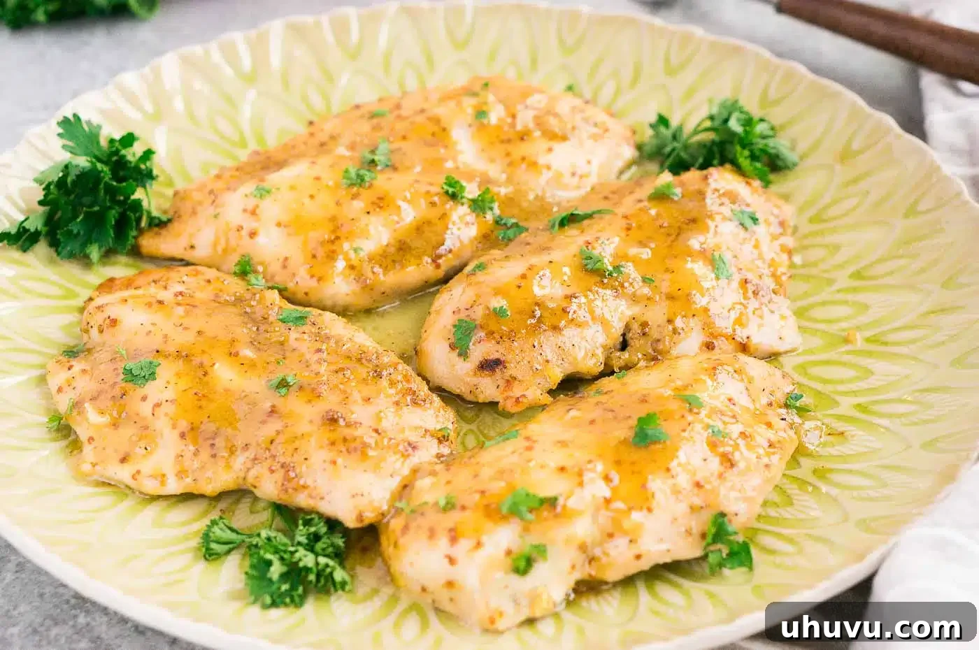 Perfectly glazed honey mustard chicken served on a plate with vibrant green garnish, ready to eat