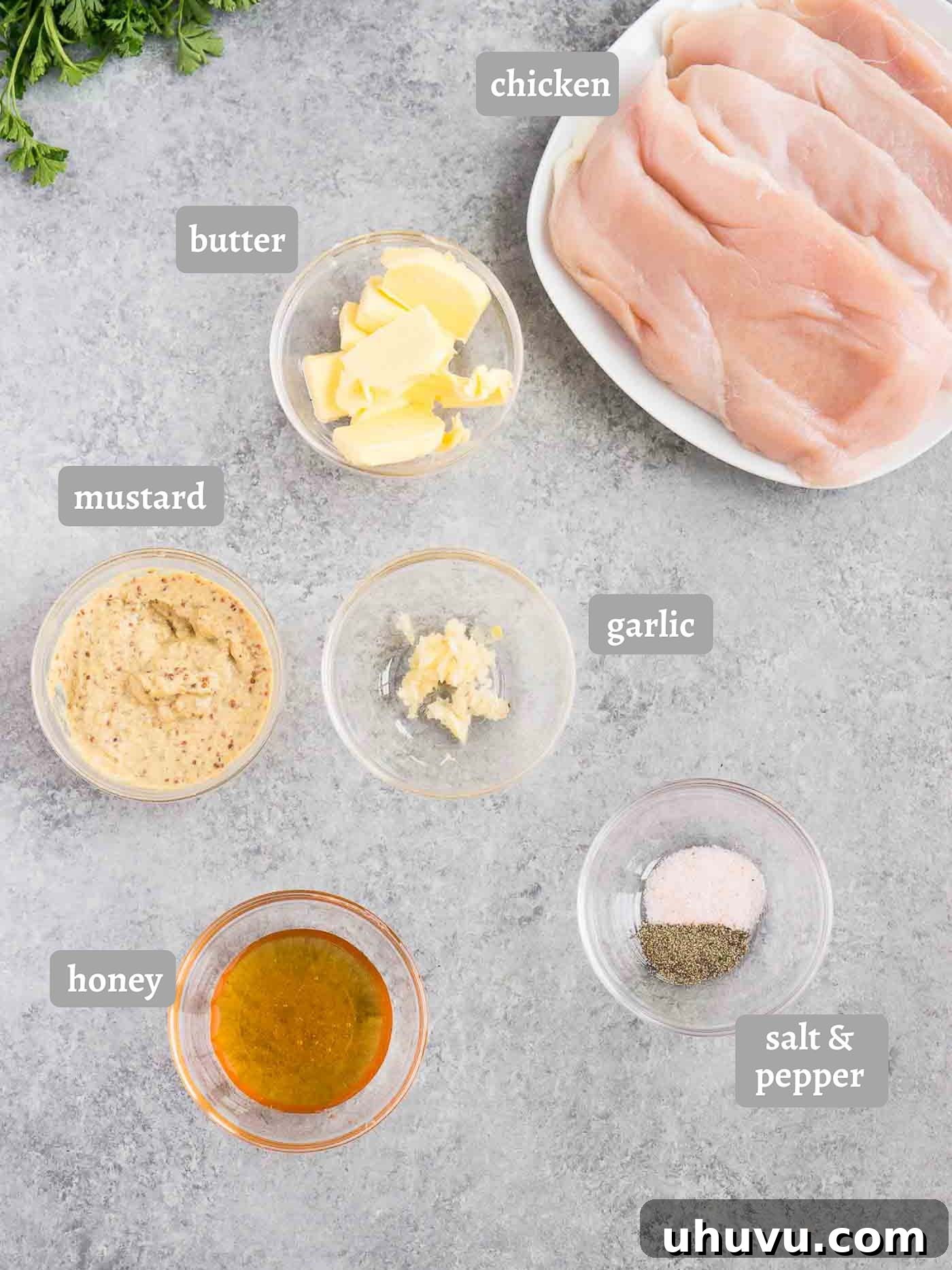 A selection of fresh ingredients including chicken, honey, various mustards, butter, and garlic, ready for cooking