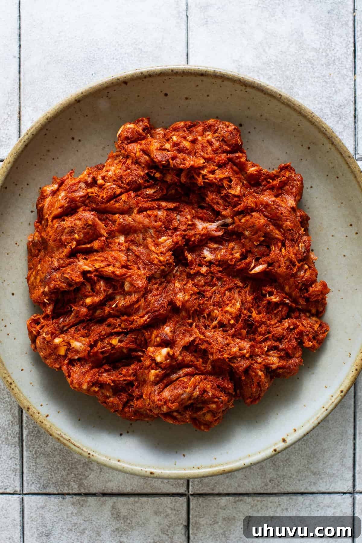 Brightly red-colored and seasoned Mexican chorizo in a bowl, before cooking.