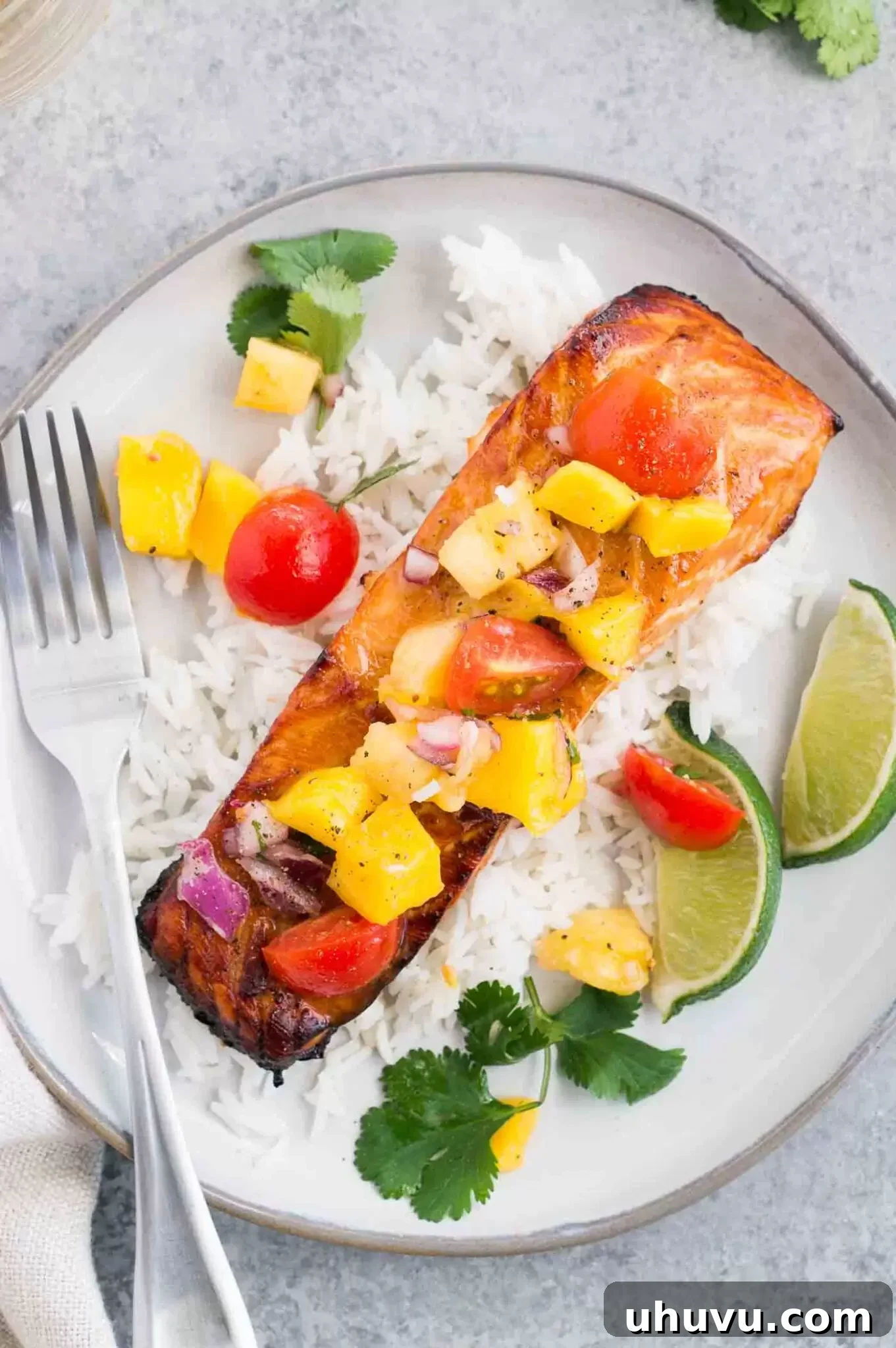 Baked salmon with mango pineapple salsa over rice on a plate