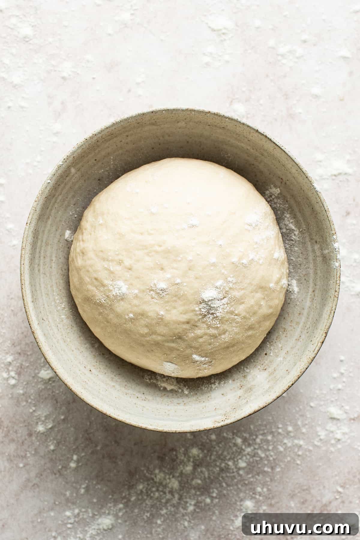 Sopapilla dough resting in a large bowl, covered with a kitchen towel.
