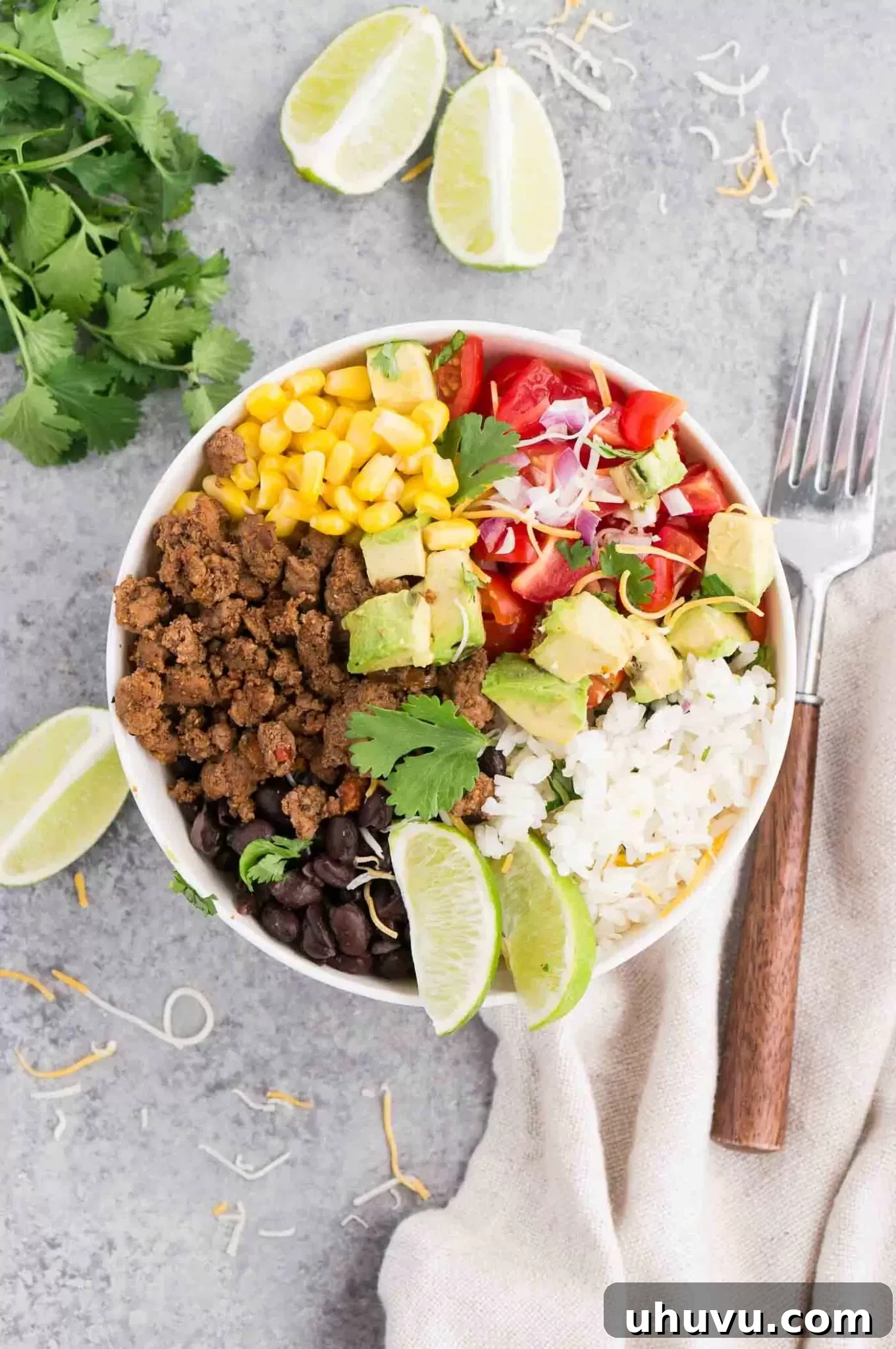 A vibrant taco bowl showcasing seasoned beef, rice, and colorful fresh vegetables.