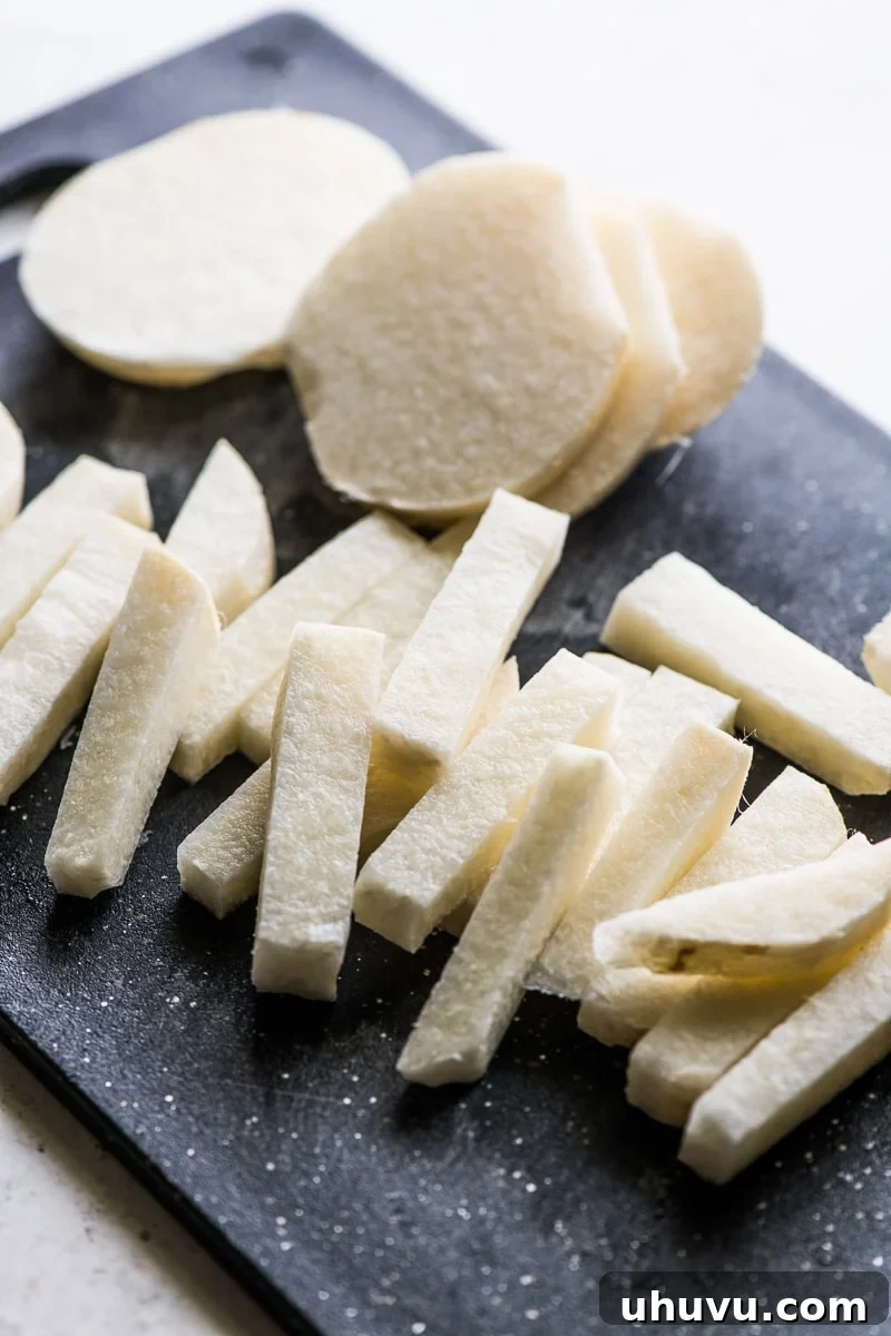 Sliced raw jicama on a cutting board, ready for culinary use.