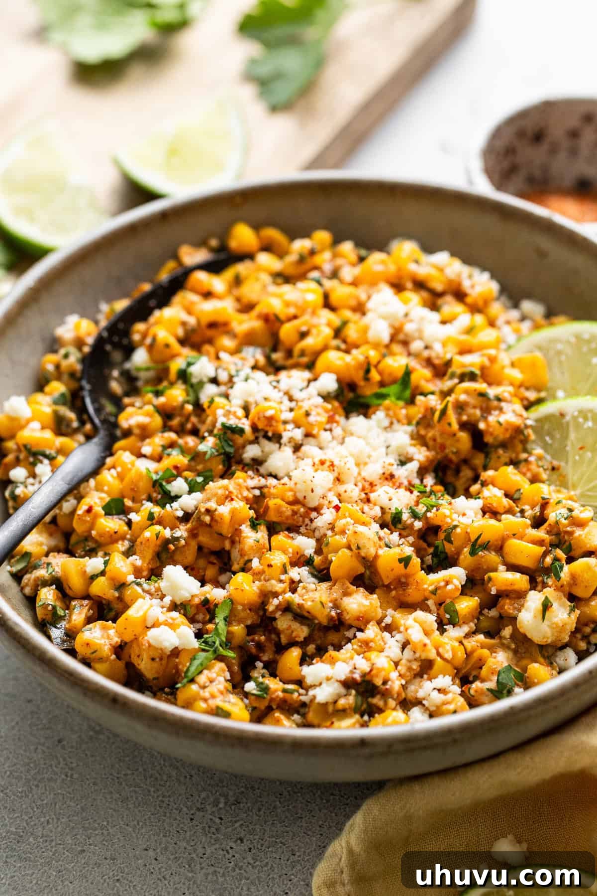 Esquites or Mexican street corn salad plated in a deep bowl, garnished with lime and chili