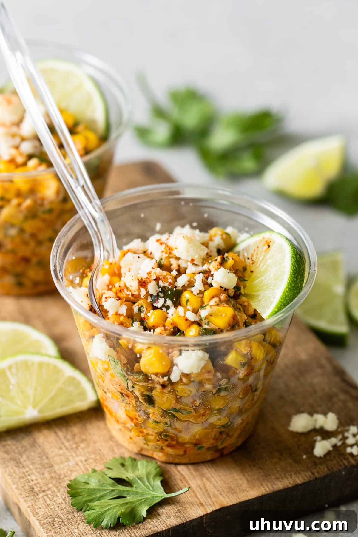 Esquites served and ready to eat in an individual cup, garnished with lime and chili