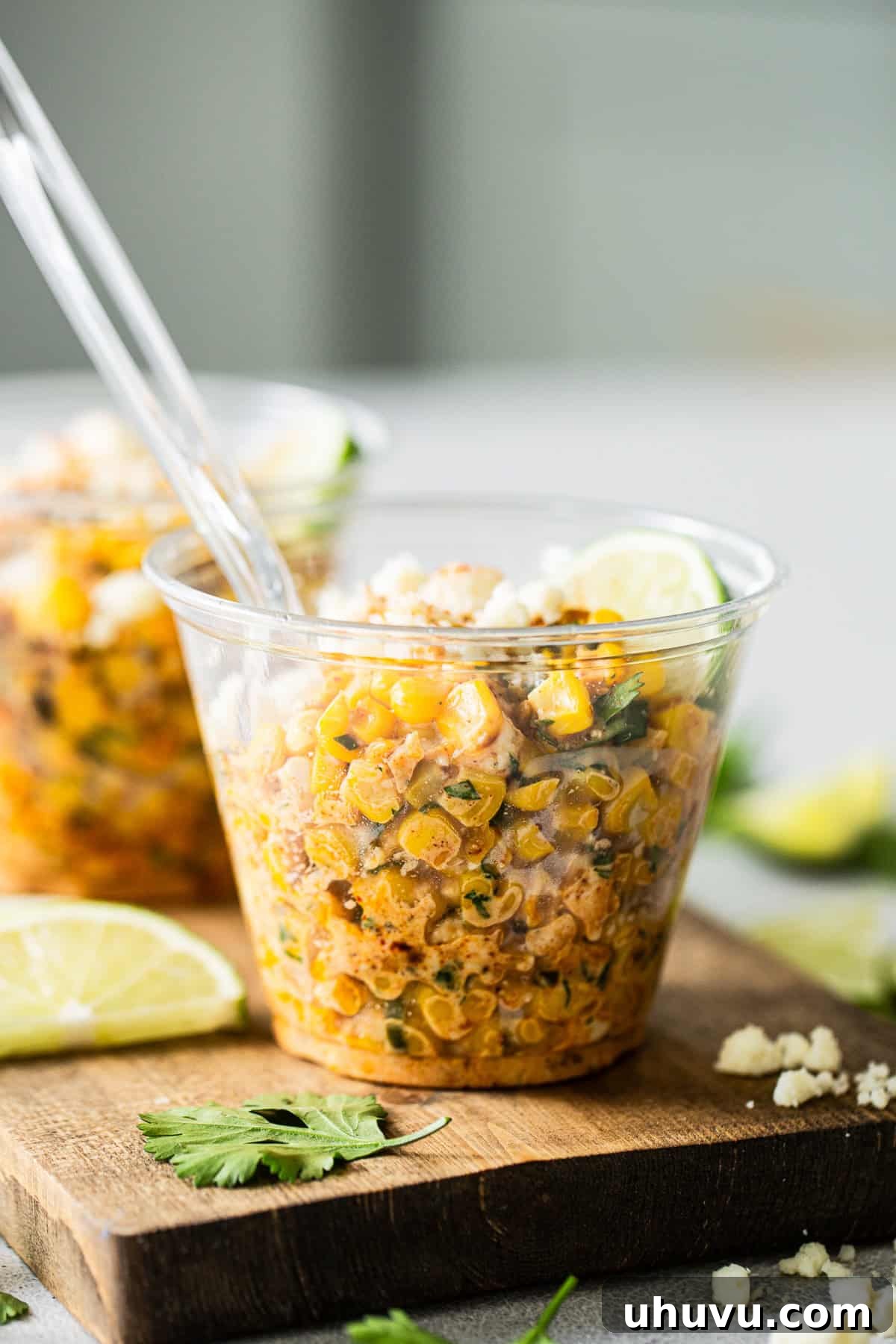 Esquites served into a cup with lime wedges and cilantro garnish
