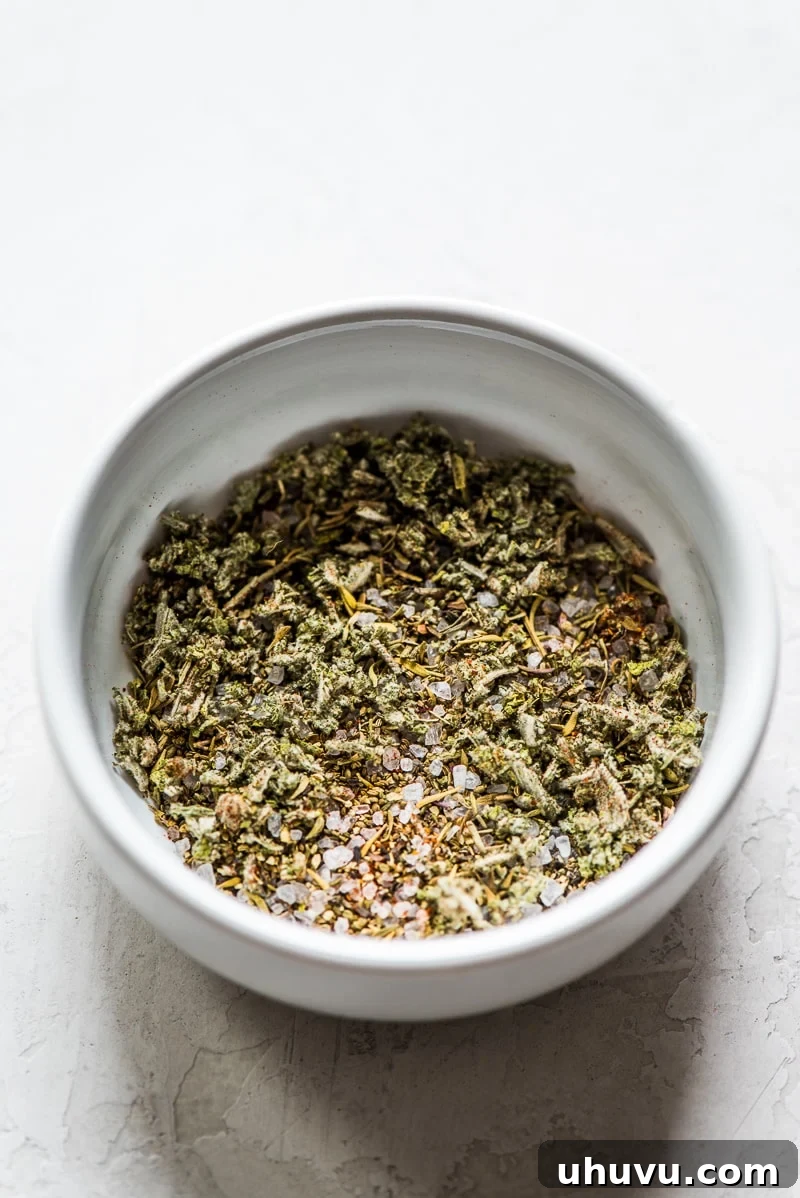 Herbs and spices for butternut squash soup in a small white bowl, including sage, thyme, paprika, salt, and pepper.