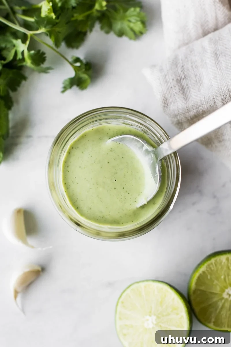 Cilantro Lime Crema 3 Cilantro lime dressing in a glass jar with a spoon in it.