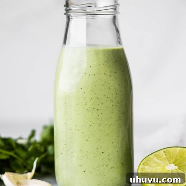 Cilantro Lime Dressing in a jar next to fresh limes and garlic cloves.