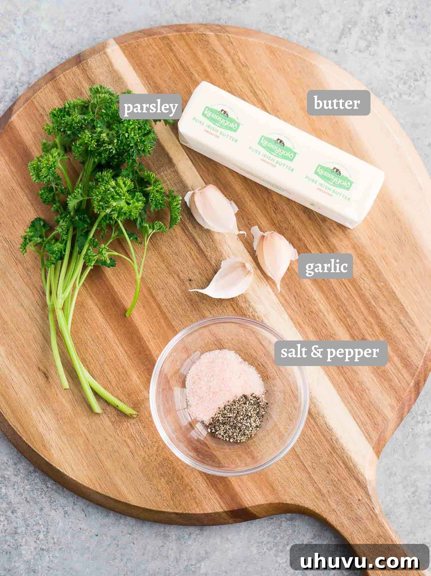 Garlic Gold 4 A flat lay image displaying all the simple ingredients required for the garlic butter recipe: softened butter, fresh garlic cloves, chopped parsley, salt, and pepper.