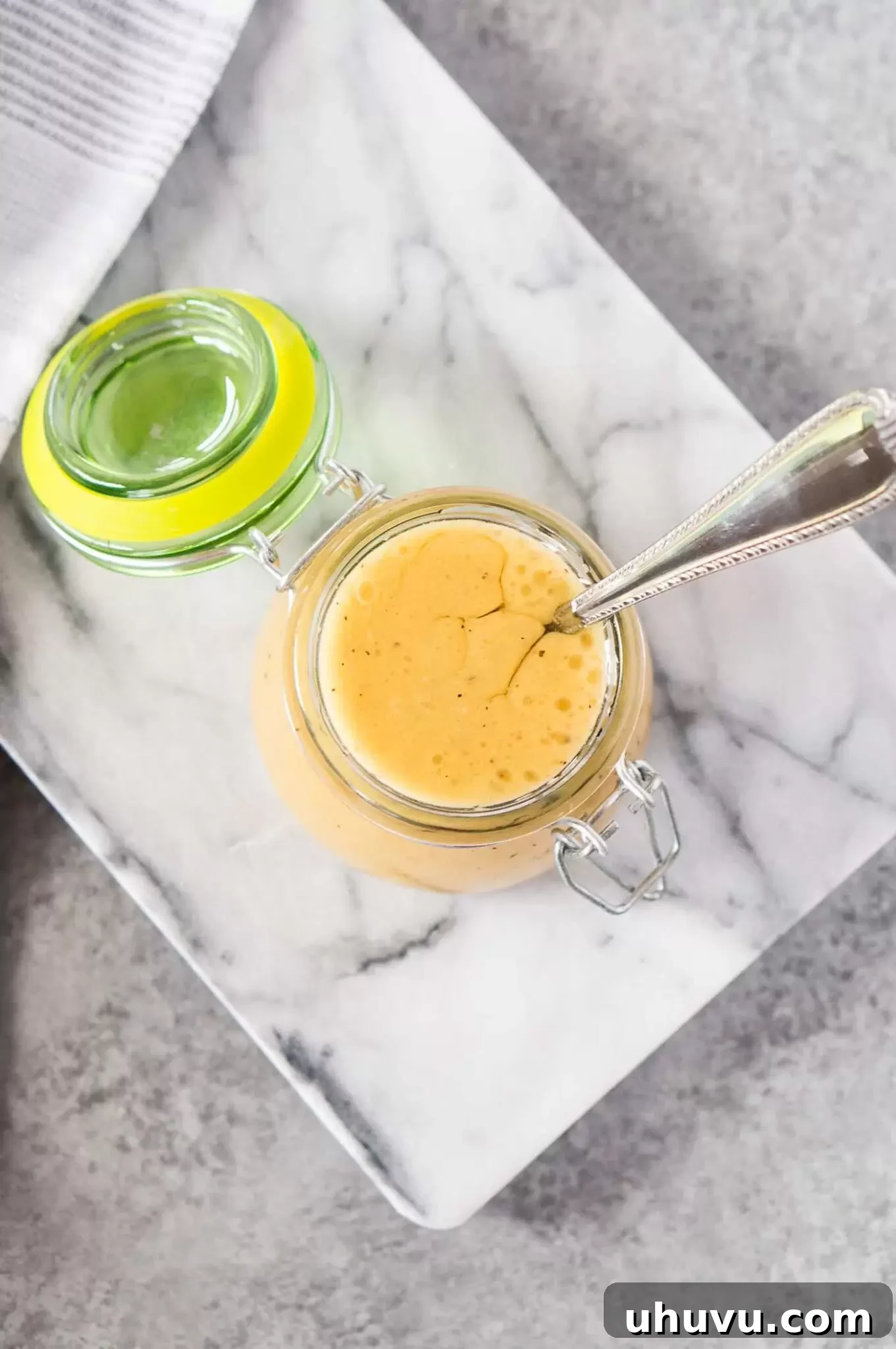 A jar of homemade honey mustard dressing, ready to pour over a fresh salad or serve as a dip.