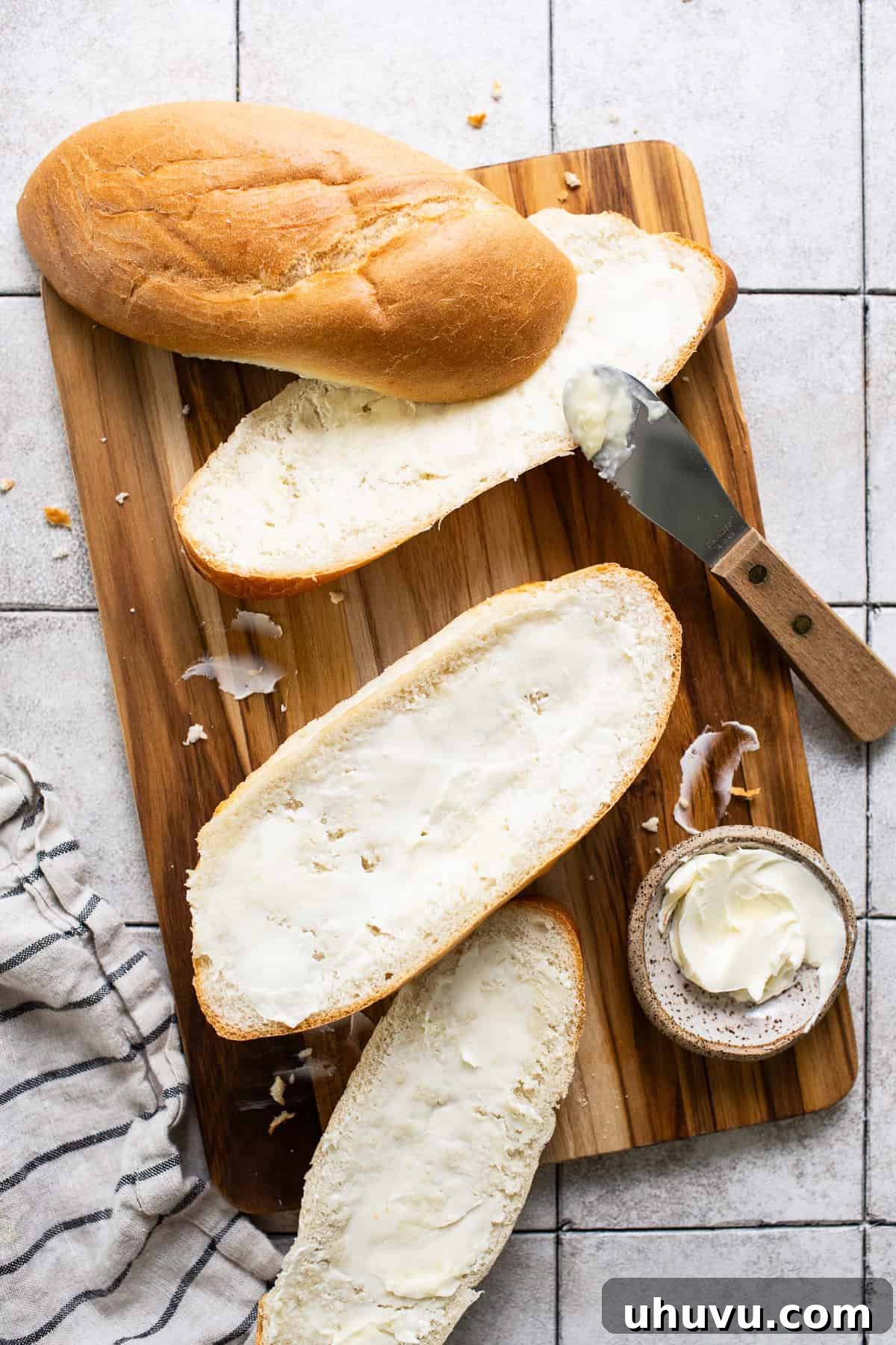 Butter spread on bolillo bread halves, ready for toasting to make molletes.
