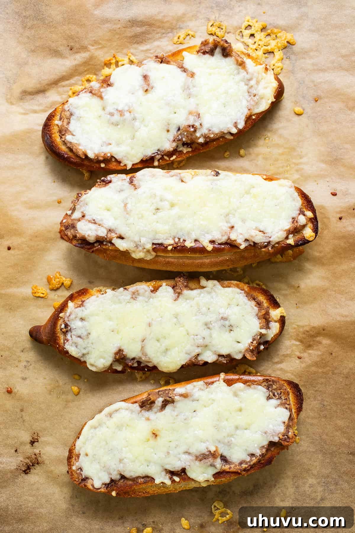 Close-up of melted, bubbly cheese on a bolillo bread half for molletes.