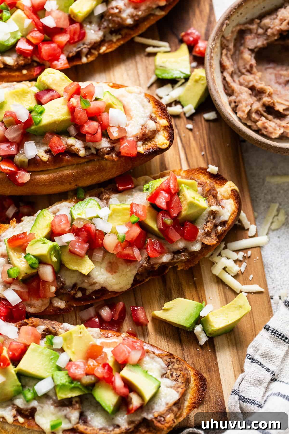 Fully prepared molletes, generously topped with refried beans, melted cheese, pico de gallo, and fresh avocado slices.