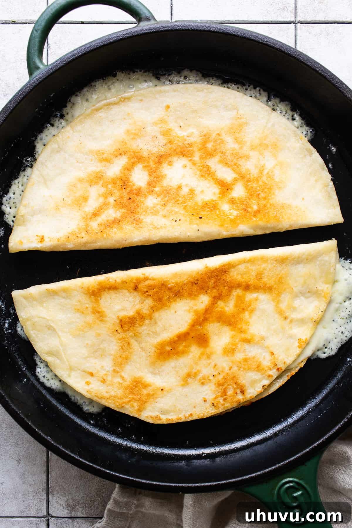 Irresistible Cheesy Quesadilla 5 Cheese quesadillas being cooked in a skillet with butter until golden brown and crispy on the outside.