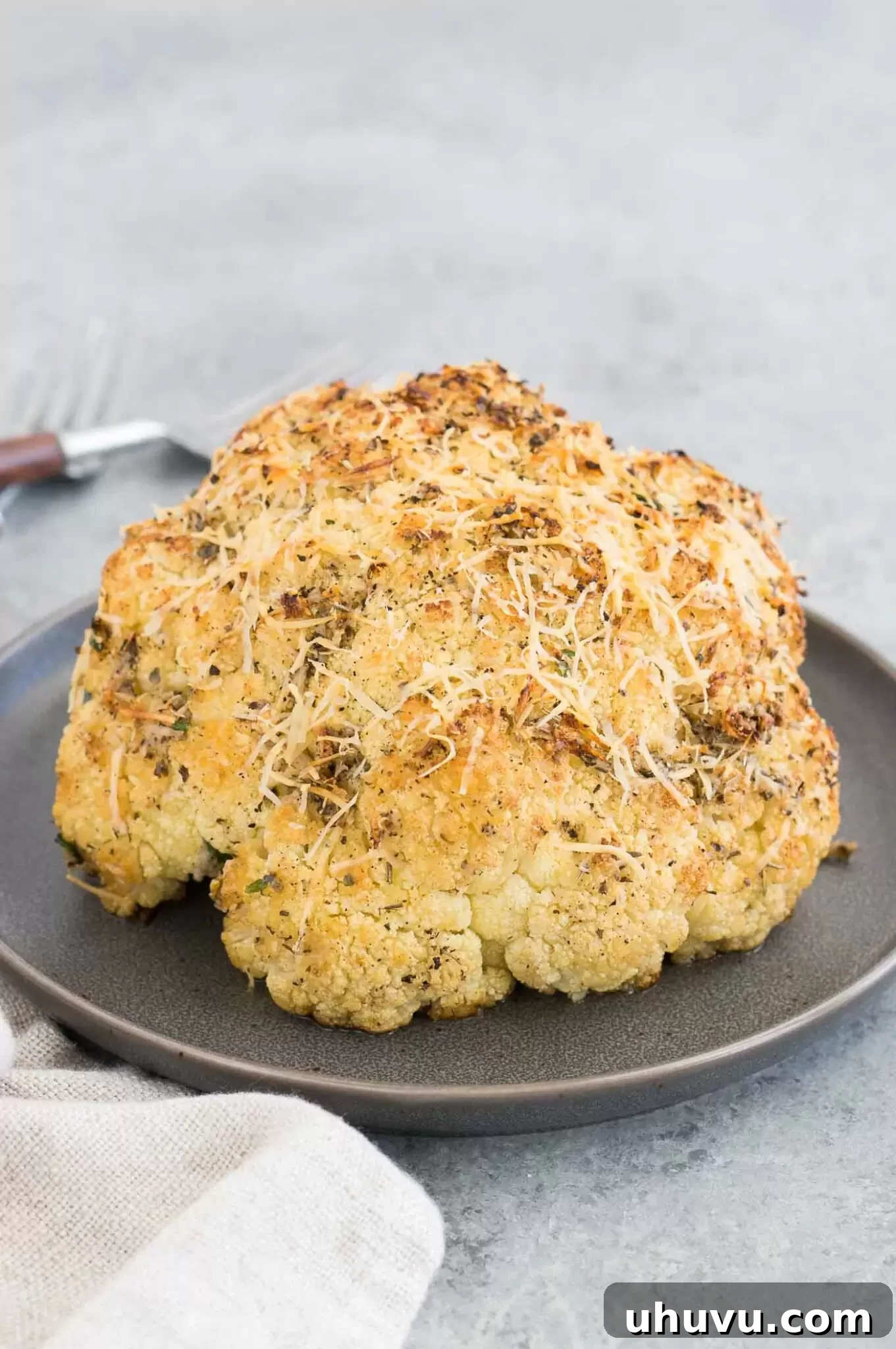 Close-up of golden brown oven roasted whole cauliflower, garnished with fresh parsley
